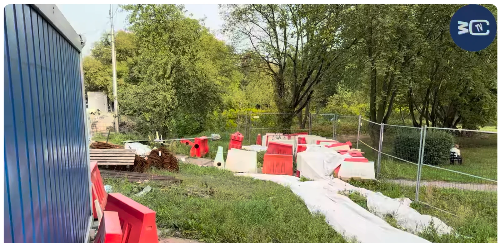 Czerwone i białe zapory oraz materiały przy tymczasowym ogrodzeniu.